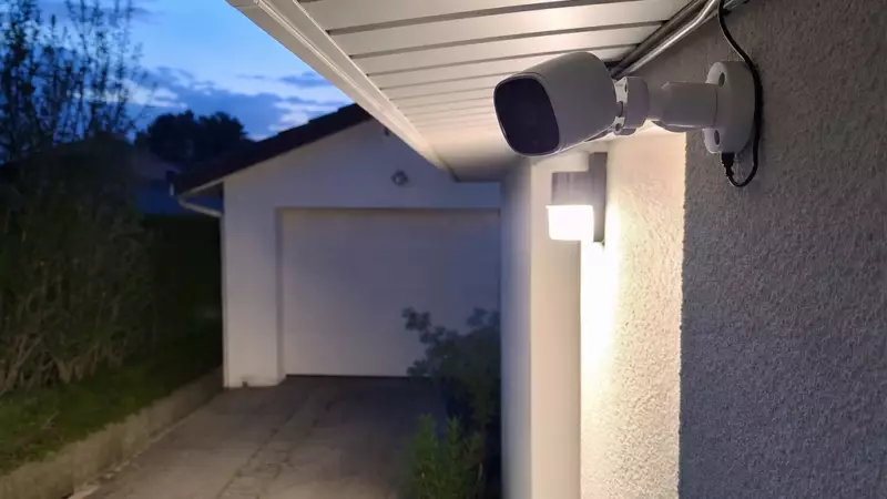 Caméra extérieure installée sous un avant-toit et éclairant une allée privée la nuit
