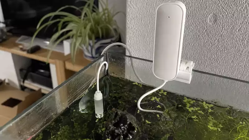 Capteur Tuya ZG-109TDS blanc fixé près d’un aquarium, avec sa sonde immergée dans l’eau